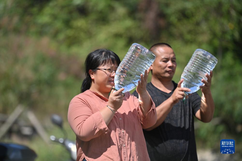 楊寧（左）在查看村民剛剛采集的水樣，為山泉水引水工程做準(zhǔn)備（10月8日攝）。新華社記者 黃孝邦 攝